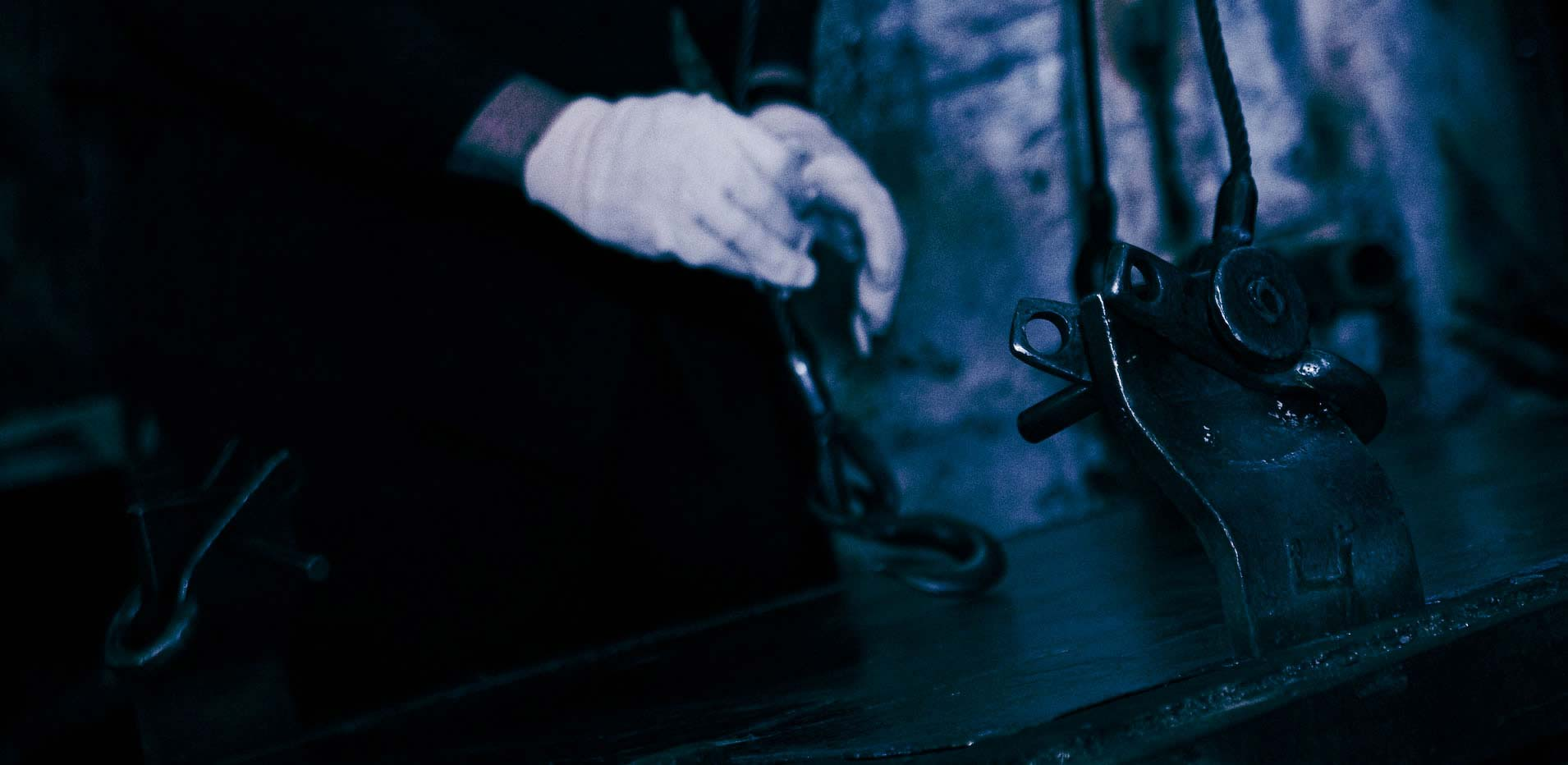 Gloved hand reaching toward industrial metal fabrication equipment