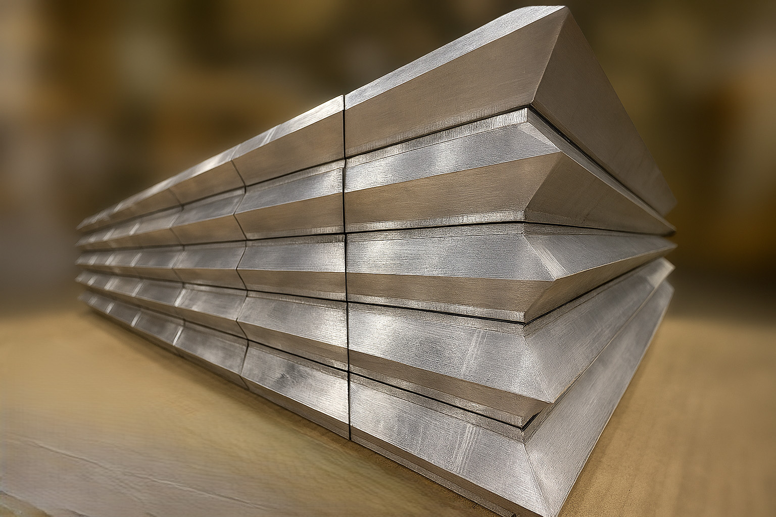 Stack of flat metal sheets arranged in offset layers on a wooden surface